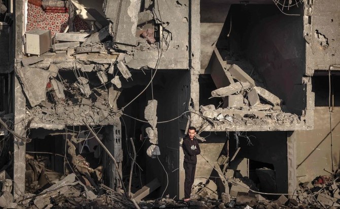 2024年1月24日、ガザ地区南部のラファ。イスラエル軍の空爆で破壊された建物の前に立つパレスチナ人男性。（AFP通信）