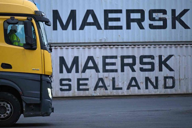 2024年1月23日、ドイツ西部の積み替えステーションで、デンマークの大手海運会社マースクのロゴ入りコンテナが積まれた横を通過するトラック。(AFP＝時事）
