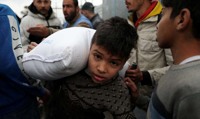 2024年1月29日、イスラエルとハマスの紛争が続く中、ガザ地区南部のラファで、国連パレスチナ難民救済事業機関(UNRWA)が配布した小麦粉の袋を運ぶパレスチナ人の少年。(ロイター)