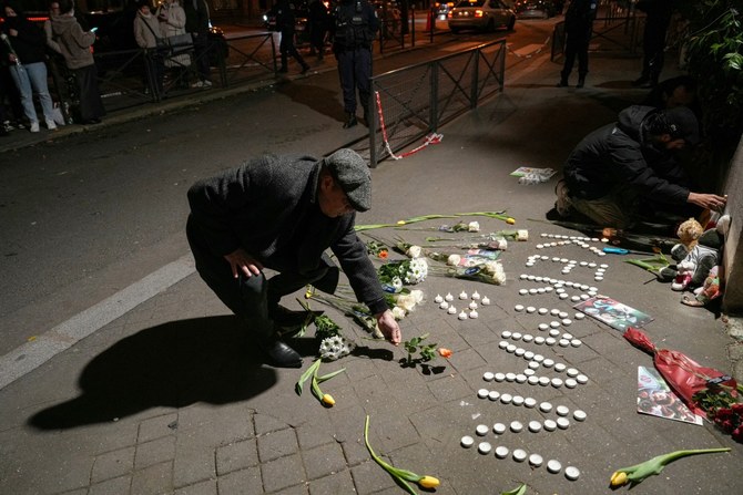 1月4日、パリのイラン大使館前で開かれた犠牲者を追悼する集会で献花する男性（AFP）