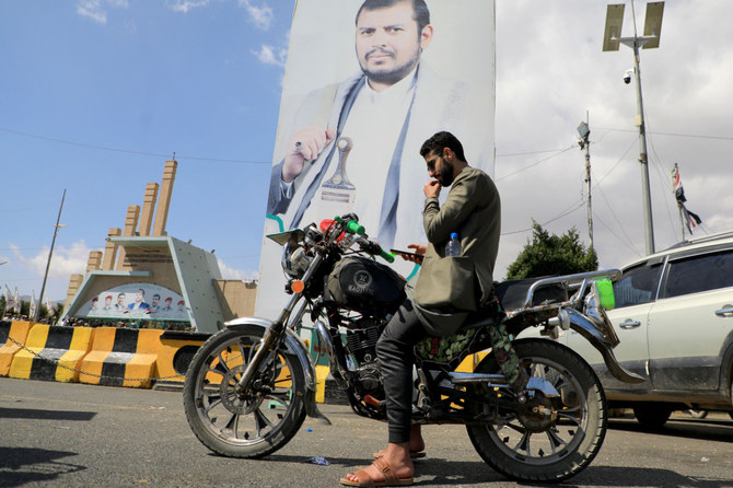 2024年1月18日、サヌアにおいて、フーシ派指導者アブドルマリク・アル・フーシ氏の写真のそばで携帯電話をチェックするイエメン人。（AFP）