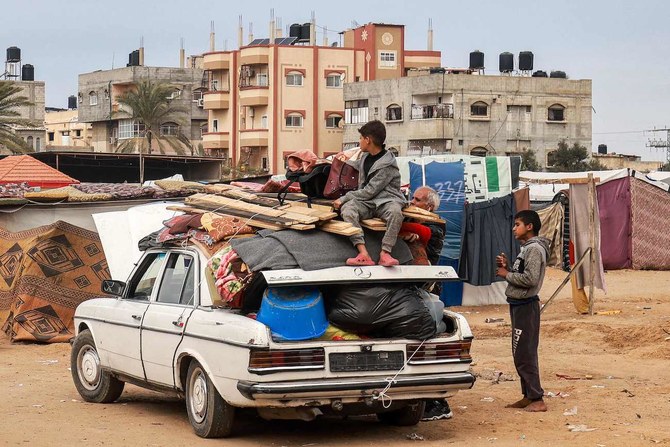 ガザ地区南部のラファから人々が避難するなか、車にロープで固定した家財の上に座る少年。2024年2月3日。(AFP)