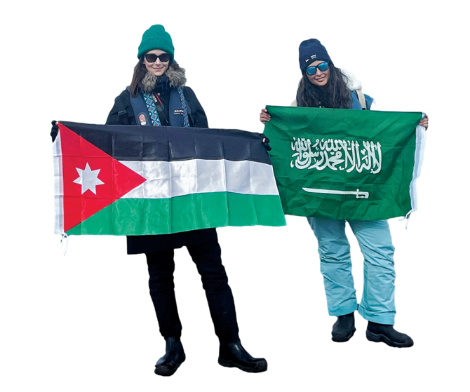 アビール王女（右）とヨルダン出身のマヤ・ビーノ氏は、凍りつく南極を視察中、それぞれの国の国旗を掲げた。提供