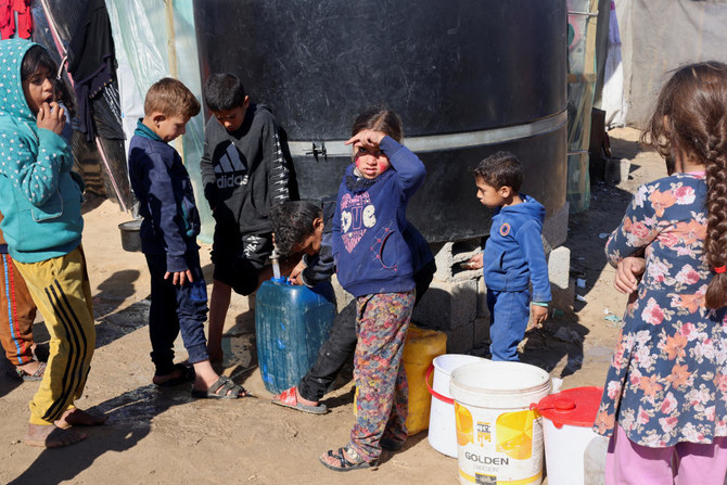 イスラエルの空爆により自宅を追われたパレスチナ避難民の子どもたちが、ガザ地区南部ラファのテント村で不足が心配される水を汲む（REUTERS）