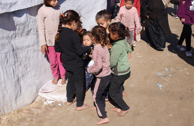 イスラエルの攻撃により自宅を追われたパレスチナ避難民の子どもたちが、新しい靴が不足するなかガザ地区南部ラファのテント村で裸足で遊ぶ。2024年1月31日。（REUTERS）
