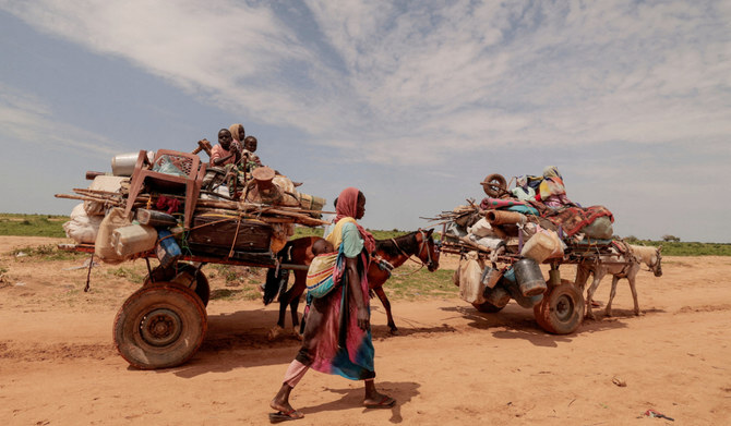 2023年8月2日、スーダンのダルフール地域のムルネイから逃れたスーダン人女性が、スーダンとチャドの国境を越える際、家族の荷物を積んだ荷車の横を歩く。（ロイター）