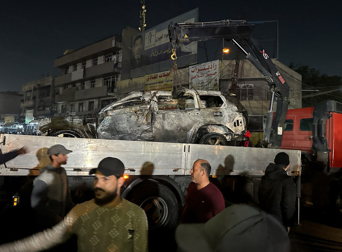 2024年2月7日、イラクのバグダッドで、治安当局者が致死的なドローン攻撃だと評した攻撃のあとに、破壊された車両を撤去する人々。（ロイター）