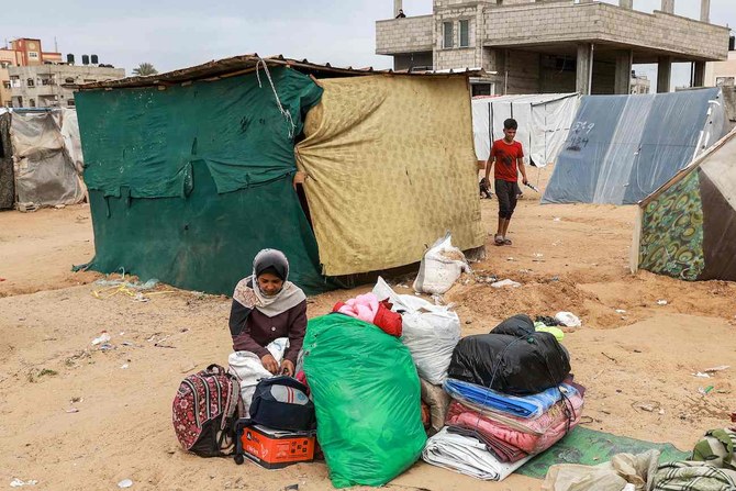 2024年2月13日、ガザ地区南部のラファから脱出する前のキャンプで、テントの近くに荷物を置いて座る女性。(AFP＝時事）