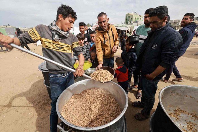2024年2月13日、ガザ地区南部のラファで、食糧不足の中、慈善団体による炊き出しを待つ子ども連れのパレスチナ人。(AFP＝時事）
