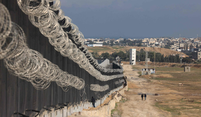 ガザ地区南部ラファで、同地区とエジプトの国境フェンスの横を歩くパレスチナ避難民。(AFP)