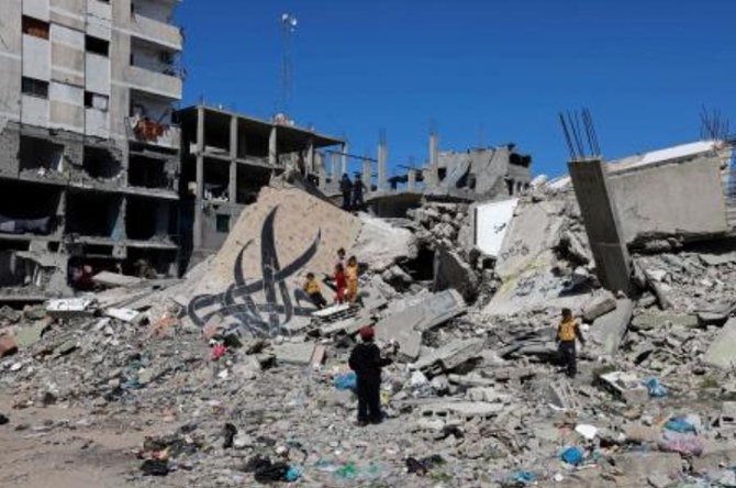 2024年2月22日、イスラエルとハマスの戦闘が続く中、ラファでイスラエルの砲撃で倒壊した建物の瓦礫の破壊された壁画の横に立つ子どもたち。（AFP）