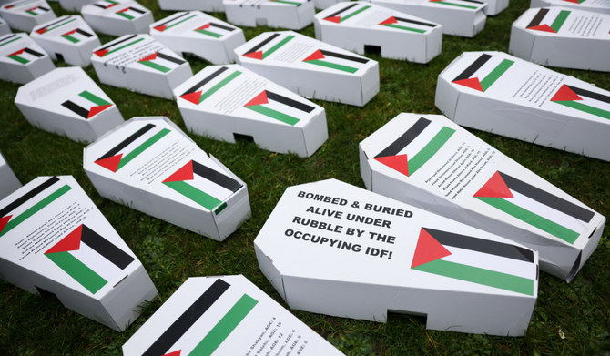 2024年2月10日、英国ロンドンで、イスラエルとパレスチナのイスラム主義組織ハマスとの紛争が続く中、ガザの犠牲者に対する追悼集会に集まったデモ参加者が芝生の上に置いた、パレスチナ国旗が描かれた模擬棺。（ロイター）