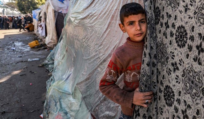 ガザ地区南部のラファで、パレスチナ人避難民を収容するテントから顔をのぞかせる子ども。2024年2月8日。（AFP）
