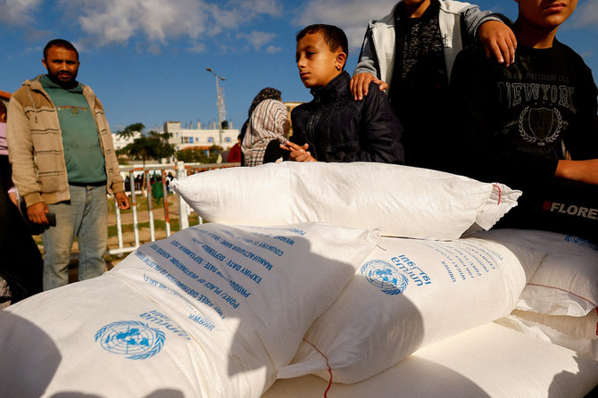2023年11月21日、ガザ地区南部のラファで、UNRWAから配布された小麦粉の袋を受け取るパレスチナ人。（Reuters）(ロイター）