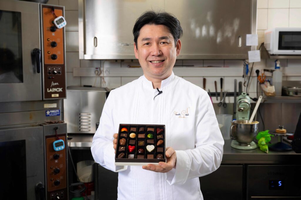 2024年3月14日、ブリュッセルのヴォルーエ＝サン＝ピエールにある工房で、チョコレートの箱を手に写真撮影に応じる日本人ショコラティエの佐々木靖氏。(AFP)