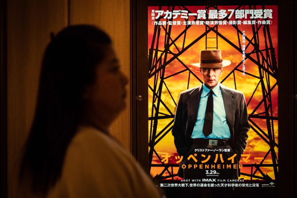 2024年3月29日、東京で「オッペンハイマー」の広告の前を通り過ぎる女性。アカデミー賞最優秀作品賞を受賞した「オッペンハイマー」が3月29日についに日本で公開された。(写真：Yuichi YAMAZAKI / AFP)