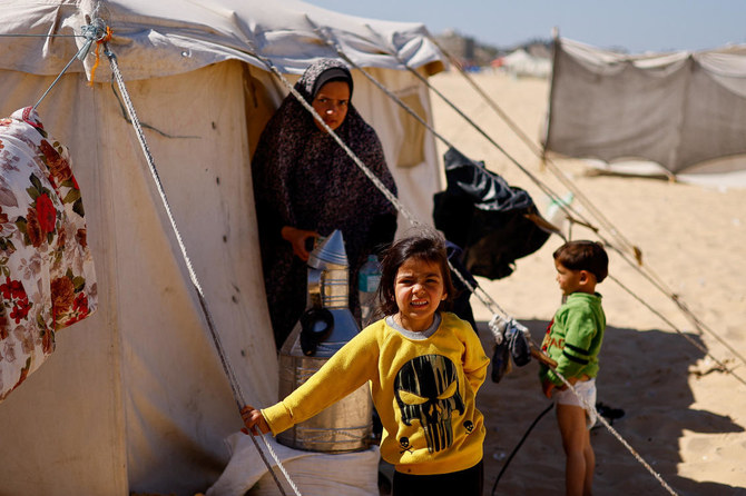 2024年2月29日、イスラエルの攻撃で家を追われたパレスチナ人難民らがラファのテントキャンプに避難してくるのを見ている子どもたち。（ロイター通信）