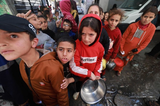 2024年3月5日、包囲されたパレスチナ領土で飢餓が広がる中、ガザ地区南部のラファで、若者ボランティア活動の一環として調理された食料を受け取るパレスチナの子どもたち。(AFP＝時事）
