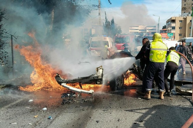 国境を越えた緊張が続く中、イスラエルとの国境に近いレバノン南部のナクーラ地区で、イスラエルの無人機による攻撃で炎上した車を放水する消防隊員。( AFP)
