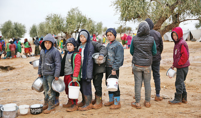 アレッポ北部の仮設キャンプで、援助隊員から配給された食料を受け取るために並ぶシリアの子どもたち。(AFP/ファイル)