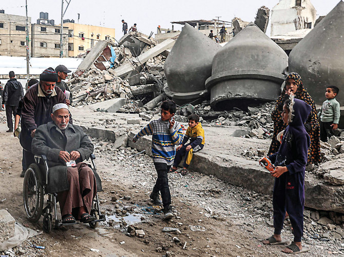 2024年3月17日、イスラエル軍の砲撃で破壊されたガザ地区南部ラファのアル・ファルク・モスクの瓦礫の前を歩く人々。(AFP）