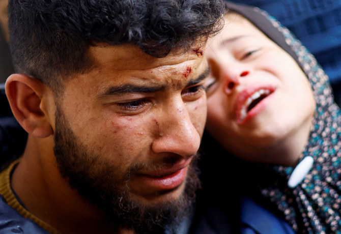 2024年3月19日、ガザ地区南部ラファの病院で、イスラエルとハマスの紛争が続く中、イスラエル軍の空爆で死亡したパレスチナ人の遺体の横で反応する弔問客。(REUTERS)