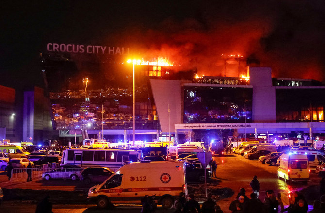 銃撃事件の後、燃え盛るクロッカス・シティ・ホールのコンサート会場に停車するロシア救急隊の救急車と車両（2024年3月22日、モスクワ郊外）。(REUTERS)