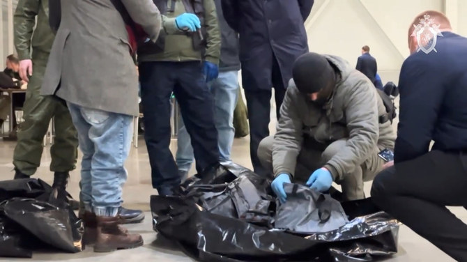 2024年3月22日にモスクワで発生したコンサート襲撃事件を調査する捜査員により、犠牲者の死体が入った遺体袋が検査される。(ロシア調査委員会 via AP）