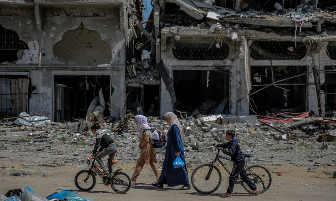 イスラエルとパレスチナ・ハマス間の紛争が続く中、ガザ地区北部で破壊された建物の横を歩くパレスチナ人（2024年3月21日撮影）。(AFP）