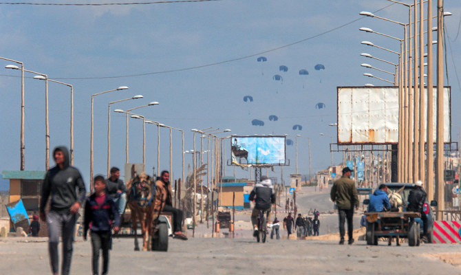 2024年3月25日、イスラエルと過激派組織ハマスの間で紛争が続くパレスチナ自治区で、ガザ市西部のガザ地区に人道援助物資が投下され、海岸沿いの道路を行き交う人々。(AFP＝時事）