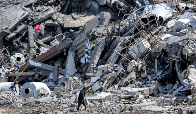 2024年3月25日、パレスチナ自治区でイスラエルと過激派組織ハマスとの間で紛争が続く中、ガザ地区ヌセイラット北西のアスラ住宅地で、破壊された建物の瓦礫の近くを歩き、引き揚げ物を探す男性。(AFP＝時事）