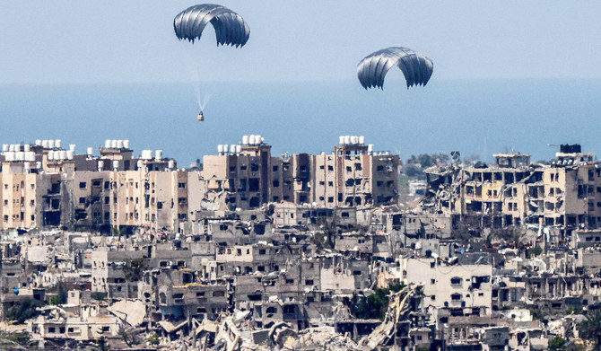 2024年3月26日、イスラエルと過激派組織ハマスとの間で紛争が続く中、包囲されたパレスチナ自治区上空に人道支援物資のパラシュートが落下する様子を、イスラエル南部とガザ地区との国境から撮影した写真。(AFP＝時事）