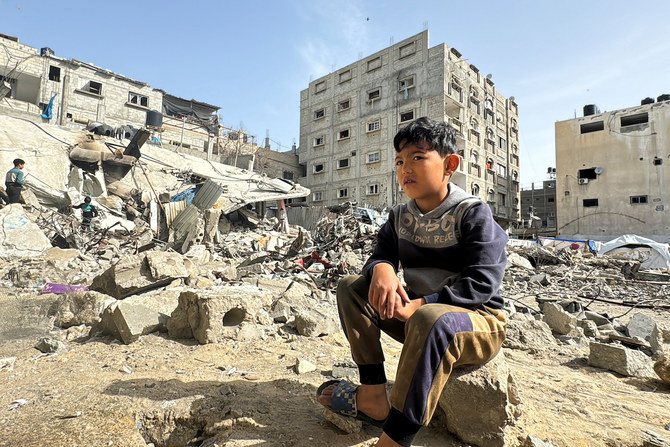 2024年3月27日、ガザ地区南部のラファで、イスラエル軍の空爆跡地に座り込むパレスチナ人の少年。(ロイター）