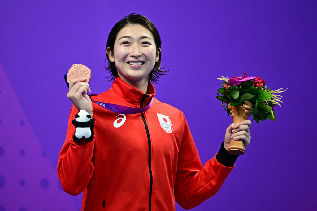2023年9月29日、中国東部の浙江省杭州市で開催された2022年杭州アジア大会の競泳女子50メートルバタフライのメダルセレモニーで、表彰台で喜ぶ銅メダルの池江璃花子。(AFP＝時事)