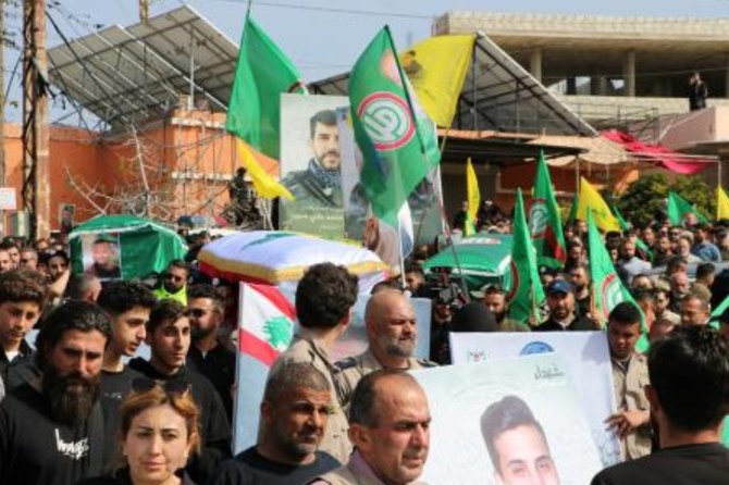 2024年3月28日、レバノン南部の国境沿いの村ナクーラで、一夜にしてイスラエル軍の空爆で死亡した4人の棺を国旗を掲げて運ぶ弔問客。(AFP＝時事）