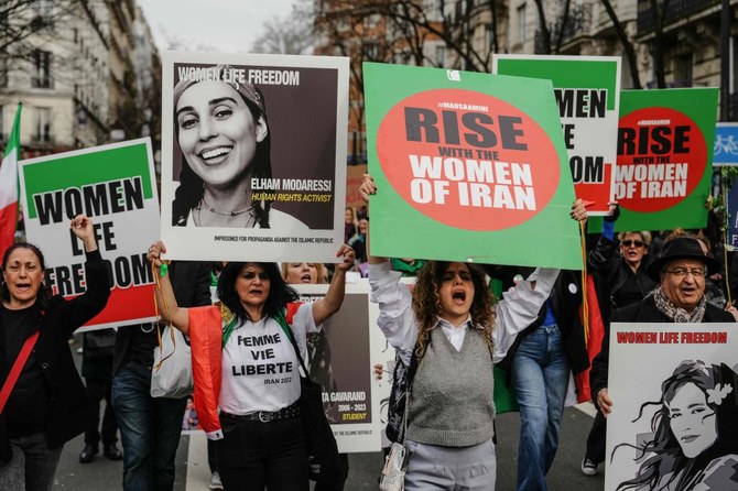 2024年3月8日、国際女性の権利デーの一環としてパリで行われたデモ行進で、反政府デモに参加した容疑でイランで拘束されているイラン人アーティスト、エルハム・モダレシ（左から2人目）（「モダレシ」または「モダレシ」とも表記される）の肖像を含む、イランの女性活動を支持するプラカードを掲げるデモ参加者たち。(AFP＝時事）