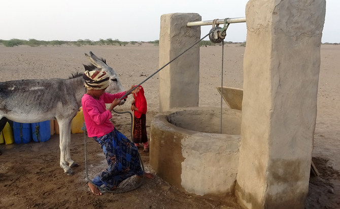 フーシ派とサウジアラビア政府軍の戦闘から逃れてきた人々のための即席キャンプで、井戸からバケツで水をくみ上げるイエメンの少女。(AFP＝時事）