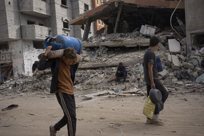 2024年4月8日月曜、ガザ地区南部のハーン・ユーニスで、イスラエル軍の空爆と地上攻撃の後、瓦礫の中を歩くパレスチナ人。(AP）