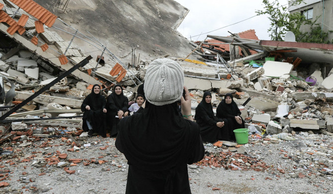レバノン南部のアイタ・アル・シャアブ村の住民が、イスラエル軍の砲撃で破壊された家屋の前で撮影。(AFP＝時事通信）