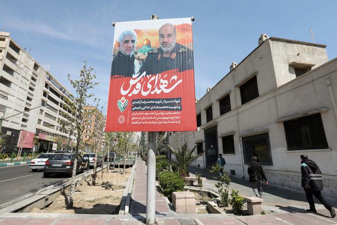 2024年4月3日、ダマスカスのイラン大使館空爆で殺害されたモハマド・レザ・ザヘディ司令官とモハマド・ハディ・ハジ・ラヒミ副司令官の肖像画の前を通り過ぎる人々。(AFP＝時事通信）