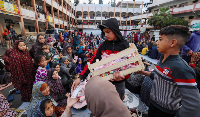 イスラエルと過激派組織ハマスの対立が続く中、2024年4月10日、ガザ地区南部ラファの学校兼避難所で、聖なるラマダン(断食月)明けを祝うイード・アル・フィトル(Eid al-Fitr)の朝の礼拝に参加する避難民に菓子を配る少年。(AFP=時事通信)