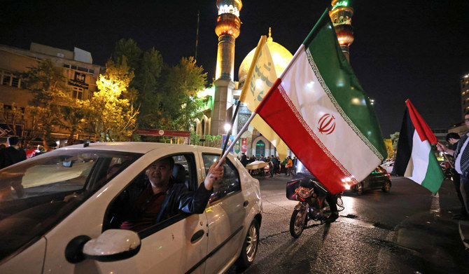 2024年4月14日、イランがイスラエルにドローンとミサイル攻撃を行った後、テヘランのパレスチナ広場に集まったデモ隊は、イランの国旗とパレスチナ国旗を振っている。(AFP＝時事通信）
