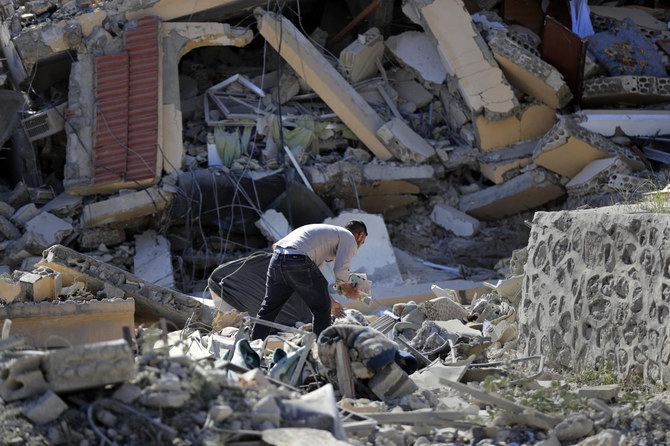 2024年4月17日水曜日、レバノン南部のマンスーリ村で、イスラエルの空爆で破壊された家から本を集めるレバノン人男性。(APフォト)