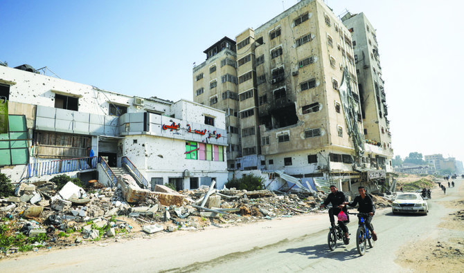 紛争が続く中、イスラエル軍の砲撃を受けたガザ最大の不妊治療クリニック、アル・バスマIVFセンターの前を自転車で通り過ぎるパレスチナ人。(ロイター）