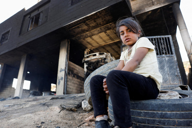 イスラエル人入植者がヨルダン川西岸地区のアルムガイル村を攻撃した後、家の前に座り込むパレスチナ人の少女。(REUTERS)