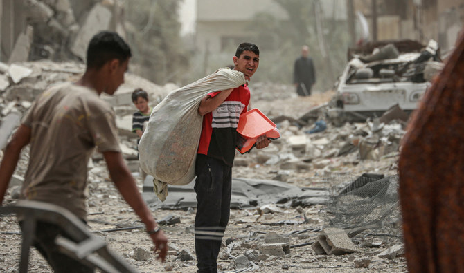 2024年4月18日、ガザ地区中央部のヌセイラットで、瓦礫の中を歩くパレスチナ人。(AFP＝時事）
