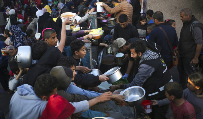 2024年3月11日、ガザ地区南部のラファで、ラマダン初日のイフタール食前に慈善団体から寄付された食料を集める避難民のパレスチナ人。(AFP＝時事）