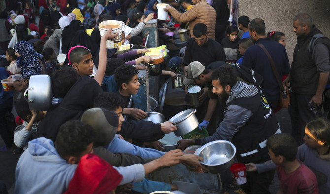 2024年3月11日、ガザ地区南部のラファで、ラマダン初日のイフタール食前に慈善団体から寄付された食料を集める避難民のパレスチナ人。(AFP=時事)