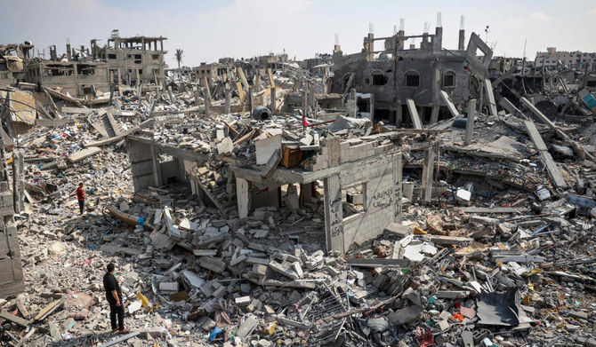 2024年4月16日、ガザ地区南部のハーン・ユーニスで、イスラエル軍の砲撃で破壊された建物の瓦礫の中で被害状況を確認する人々。(AFP＝時事）