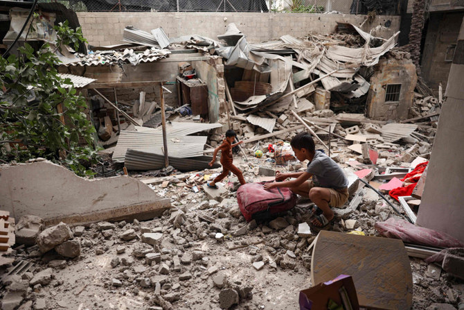 2024年4月27日、ガザ地区南部のラファで、イスラエル軍の砲撃により破壊された家屋の瓦礫から物を拾い集めるパレスチナ人の子ども。(AFP＝時事）